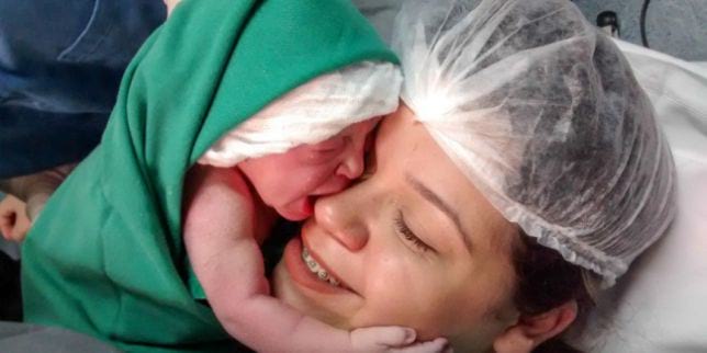 Очень эмоциональный момент: новорожденная малышка обимает лицо мамы